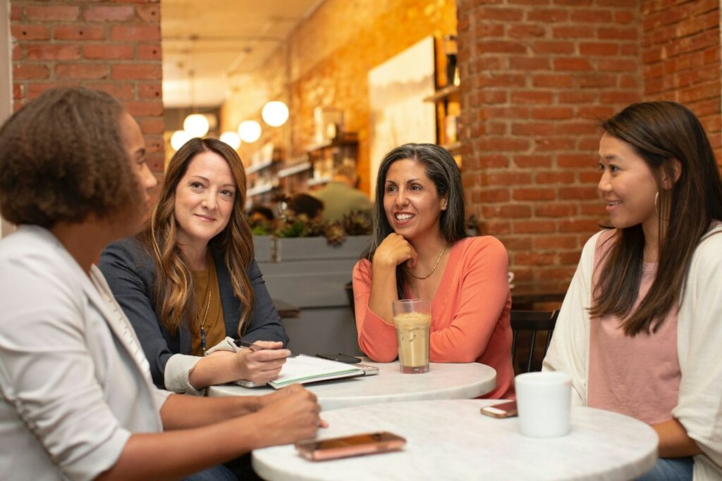 Team of professional women working at a coffee shop and discussing their mid-year check-in