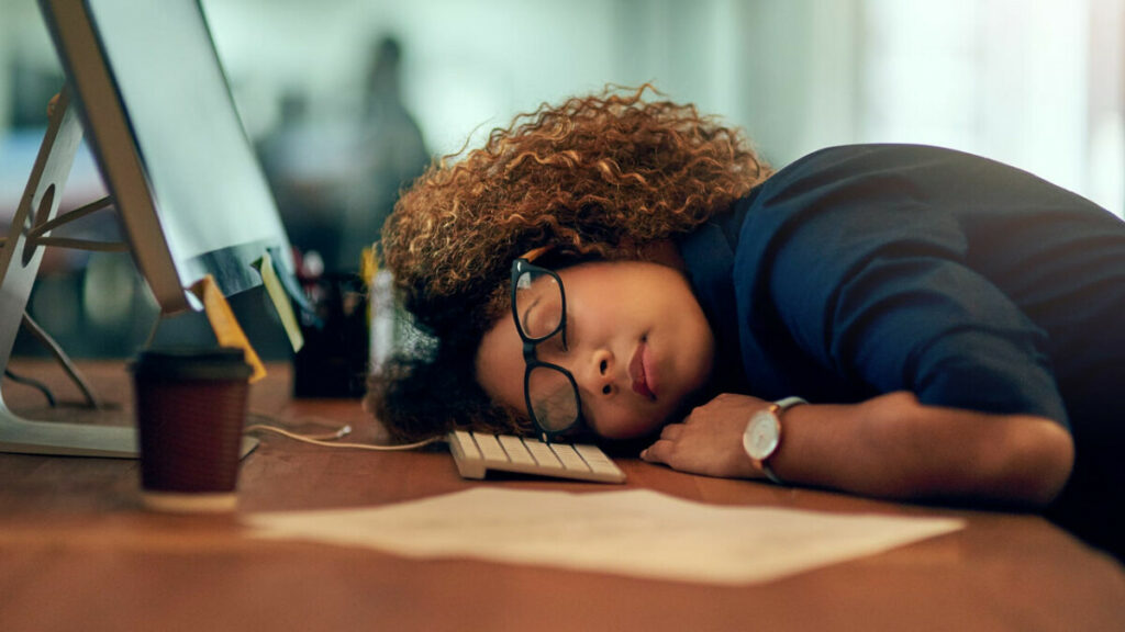 Woman business owner sleeping at desk before her mid-year check-in